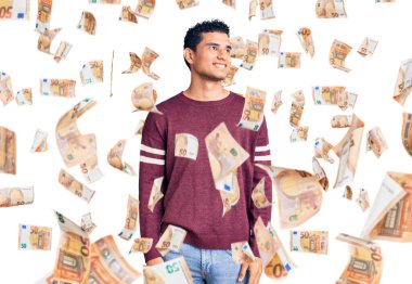 İspanyol yakışıklı, sıradan kıyafetler giyen, yüzünde gülümsemeyle yan yana bakan, doğal bir ifade. Kendinden emin gülen.