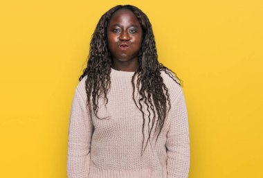 Yün süveter giyen genç Afrikalı bir kadın komik suratıyla yanaklarını şişiriyor. Havayla şişmiş ağız, çılgın bir ifade.. 