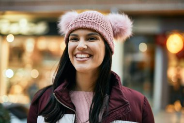 Genç İspanyol kız gülümseyerek şehirde mutlu mesut dikiliyor..