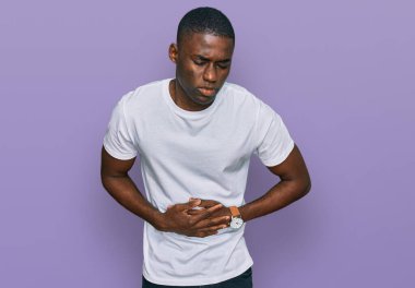 Afro-Amerikalı genç bir adam, hazımsızlık, acı veren hastalıklar ve karın üstü gündelik beyaz tişörtler giyiyor. Ağrı kavramı. 