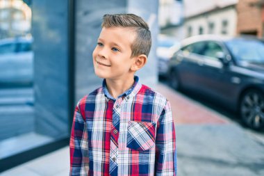 Sevimli beyaz çocuk, şehirde mutlu mesut dikiliyor..