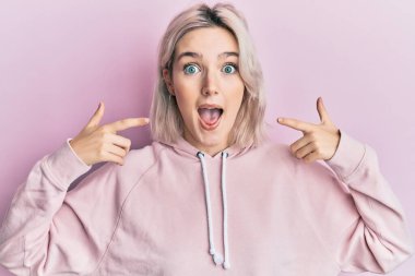 Genç sarışın kız parmaklarıyla ağzını işaret ederek çılgınlığı kutluyor ve başarıyı hayrete düşürüyor gözleri açık heyecanla bağırıyor. 