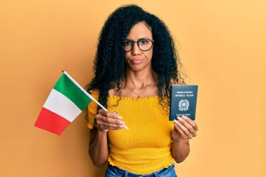 Orta yaşlı Afro-Amerikalı kadın elinde İtalyan bayrağı ve pasaport kuşkucu ve gergin, sorun yüzünden surat asıyor. negatif kişi. 