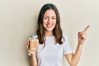 Genç esmer kadın elinde kavanozla pilav tutarken mutlu bir şekilde gülümsüyor. 