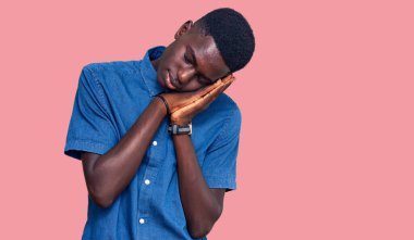 Genç Afro-Amerikan adam günlük kıyafetler giyip uyuyordu. Yorgundu. Hayal kuruyordu ve elleriyle poz veriyordu.. 