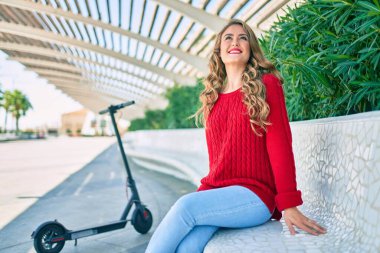 Parktaki bankta mutlu gülümseyen genç sarışın kız..