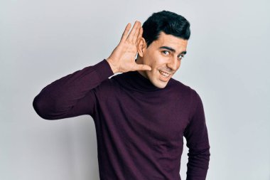 Balıkçı yaka kazak giyen yakışıklı, ağzı kulaklarında gülümseyen dedikoduları ve dedikoduları dinleyen. Sağırlık kavramı. 