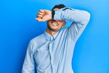 Gündelik kıyafetler giyen, gözlük takan, kollarıyla gözlerini kapatan neşeli ve komik gülümseyen genç bir İspanyol. kör kavram. 