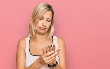 Orta yaşlı beyaz kadın günlük kıyafetler giyiyor. Ellerinde ve parmaklarında ağrı var. Eklem iltihabı. 