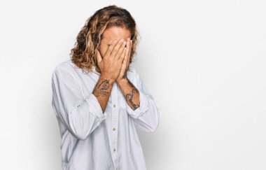 Sakallı, uzun saçlı, sıradan kıyafetler giyen, suratını ellerle örten ve ağlayan yakışıklı bir adam. depresyon kavramı. 