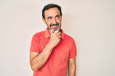 Orta yaşlı İspanyol bir adam. Elleri çenesinde gündelik giysiler giyip soru soruyor. Düşünceli bir ifade. Düşünceli bir yüzle gülümsüyor. şüphe kavramı. 