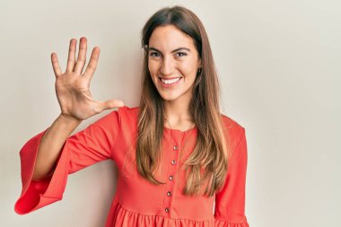 Genç ve güzel bir kadın gündelik giysiler giyer ve beş numarayı göstererek gülümserken kendinden emin ve mutlu görünürdü.. 