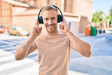 Genç İrlandalı gülümseyen mutlu müzik dinleyen şehir caddesinde kulaklık kullanan.