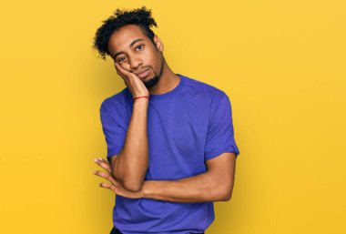 Sakallı, sıradan mor tişörtlü, depresyondan sıkılmış ve yorgun görünen genç Afro-Amerikan bir adam.. 