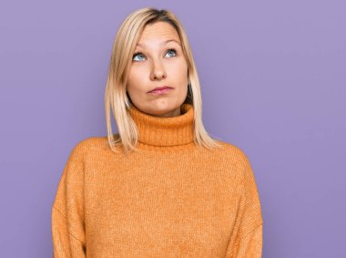 Orta yaşlı beyaz kadın, sıradan bir kazak giyiyor. Gülümsüyor, yan tarafa bakıyor ve düşünüyor.. 