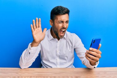 Yakışıklı İspanyol bir adam akıllı telefona el sallıyor kızgın ve kızgın çığlıklar atıyor öfkeyle bağırıyor. öfke ve agresif konsept. 