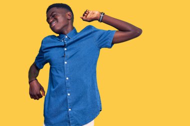 Genç Afro-Amerikan adam, günlük giysiler giymiş, yorgun ve rahat, uykulu ve sabahın erken saatleri için esniyor. 