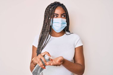 Saç örgüsü takmış, el dezenfektanı kullanan kızgın, öfkeli ve öfkeli sinirli sinirli, öfkeyle bağıran Afro-Amerikalı genç bir kadın. öfke ve agresif konsept. 