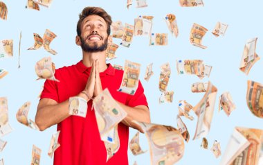 Sarışın, sakallı, sıradan kıyafetler giyen, elleri bağlı, yalvaran, dua eden, yüzünde umut ifadesi olan yakışıklı, duygusal ve endişeli bir adam. Yalvarıyor.