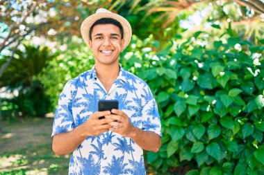 Genç Arap turist yaz stili giyiniyor. Şehir caddesinde akıllı telefon kullanıyor..