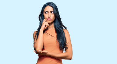 Yazlık elbise giyen güzel İspanyol kadın ciddi bir yüz ifadesi takınıyor eli çenesinde soru soran, kafa karıştırıcı bir fikir hakkında düşünceli. 