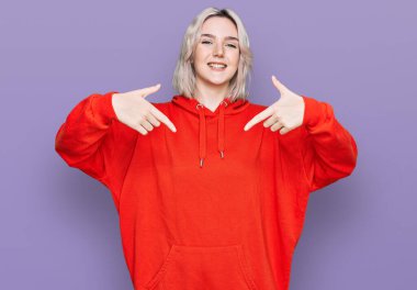 Gündelik kıyafetler giyen, kendine güvenen, gülümseyen, kendini gururlu ve mutlu gösteren genç sarışın kız.. 