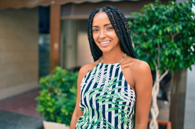 Genç Afrikalı Amerikalı kadın gülümseyerek şehirde mutlu mesut yürüyor..