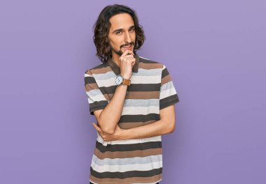 Gündelik kıyafetler giyen genç İspanyol adam kameraya kendinden emin bakıyor kollarını kavuşturup gülümsüyor ve çenesini kaldırıyor. Olumlu düşünmek. 