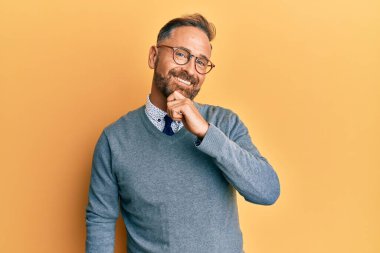 Yakışıklı, orta yaşlı, gözlüklü, gülümseyen kolları çapraz ve çenesi açık kameraya bakan bir adam. Olumlu düşünmek. 