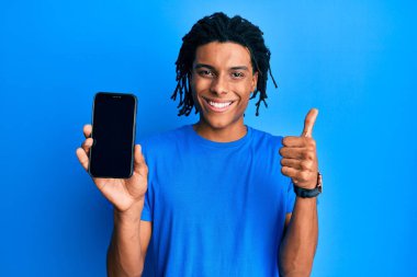 Genç Afro-Amerikan adam elinde akıllı telefonuyla boş ekranda gülümsüyor mutlu ve pozitif, başparmağıyla mükemmel ve onay işareti yapıyor. 