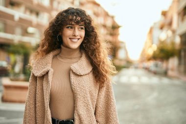 Genç İspanyol kadın gülümseyerek şehirde mutlu mesut dikiliyor.