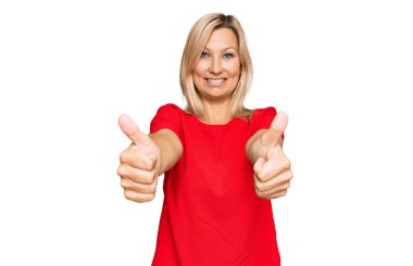 Orta yaşlı beyaz kadın, günlük giysiler giyip, olumlu jestler yapıyor, gülümsüyor ve başarı için seviniyor. kazanan jest. 