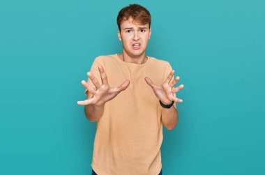 Günlük kıyafetler giyen, korku ifadesinden korkan ve dehşete düşmüş beyaz bir genç. El kol hareketi yapmayı kes, şok içinde bağır. panik konsepti. 