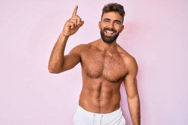 Genç İspanyol adam tişörtsüz, başarılı bir fikirle parmakla işaret ediyor. Heyecanlı ve mutlu. Bir numara.. 