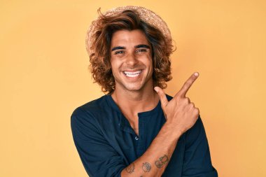 Yüzünde kocaman bir gülümseme olan İspanyol şapkalı genç adam, kameraya el ve parmak ile bakıyor.. 