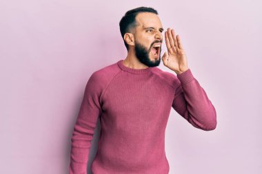 Sakallı genç adam, sıradan bir kazak giyip el ele tutuşarak bağırıyor ve bağırıyordu. iletişim konsepti. 