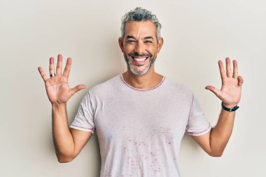 Orta yaşlı, gri saçlı, günlük kıyafetler giyen, dokuz numaralı parmaklarıyla işaret eden, kendinden emin ve mutlu bir adam.. 