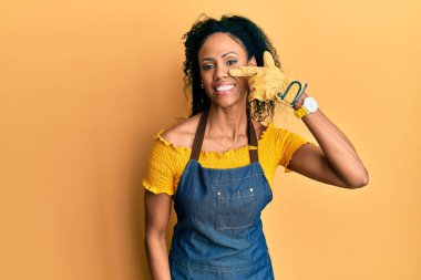 Orta yaşlı Afro-Amerikalı kadın profesyonel önlük giyip, parmaklarını birbirine göstererek, neşeli bir şekilde gülümsüyor. güzellik konsepti 