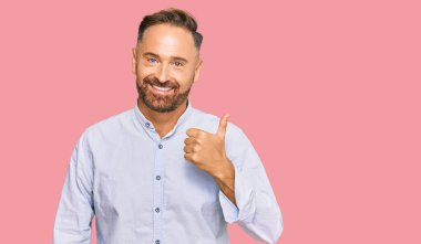 Yakışıklı, orta yaşlı, iş gömleği giyen, mutlu bir el hareketi yapan bir adam. Kameraya bakıp başarıyı gösteren ifade. 