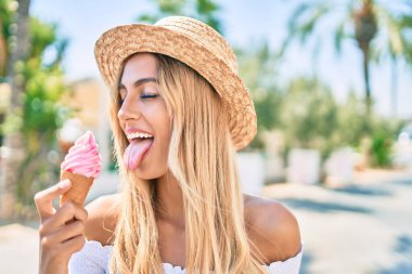 Genç sarışın turist kız gülümseyerek şehirde dondurma yiyor..