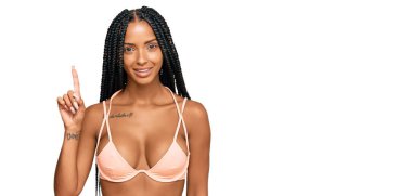 Güzel İspanyol kadın bikini giyip bir numarayı gösterip işaret ederken kendinden emin ve mutlu gülümsüyor.. 