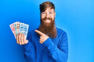 Genç İrlandalı kızıl adam Yuan 'ın Çin banknotlarını tutarken mutlu mesut elini ve parmağını gösterdi. 