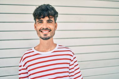 Genç İspanyol adam gülümsüyor mutlu bir şekilde şehrin duvarına yaslanıyor..