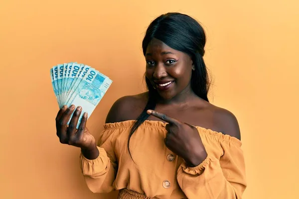 Jovem Mulher Africana Vestindo Uniforme Médico Segurando 100 Reais Brasileiros — Fotografia de Stock