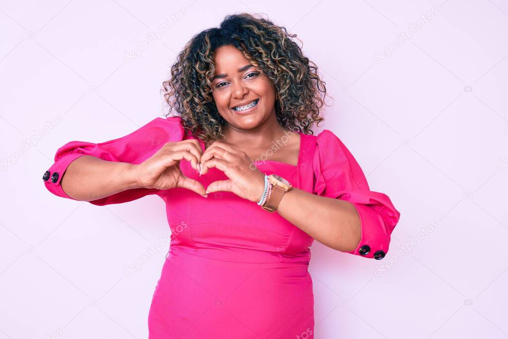 Young african american plus size woman wearing casual clothes smiling in love showing heart symbol and shape with hands. romantic concept. 