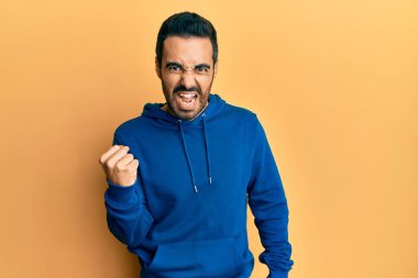 Latin asıllı genç bir adam, kızgın ve kızgın. Öfkeyle bağırırken yumruğunu sallıyor ve öfkeleniyor. öfke ve agresif konsept. 