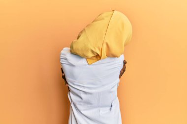 Güzel Afrikalı genç bir kadın doktor üniforması giyiyor ve tesettüre sarılmış mutlu ve pozitif bir şekilde kendini kucaklıyor. Sevgi ve özgüven. 