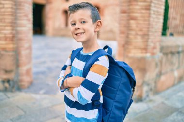 Sevimli beyaz bir öğrenci şehirde mutlu bir şekilde gülümsüyor..