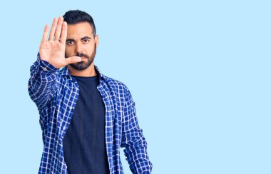 Günlük kıyafetler giyen genç İspanyol adam avucunun içi gibi şarkı söylemeyi kesiyor. Yüzünde olumsuz ve ciddi bir jest olan uyarı ifadesi. 