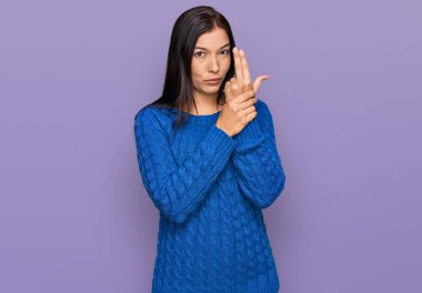 Genç İspanyol kadın gündelik kıyafetler giyiyor. Elinde sembolik bir silah var. El hareketleriyle cinayet silahlarıyla oynuyor. 